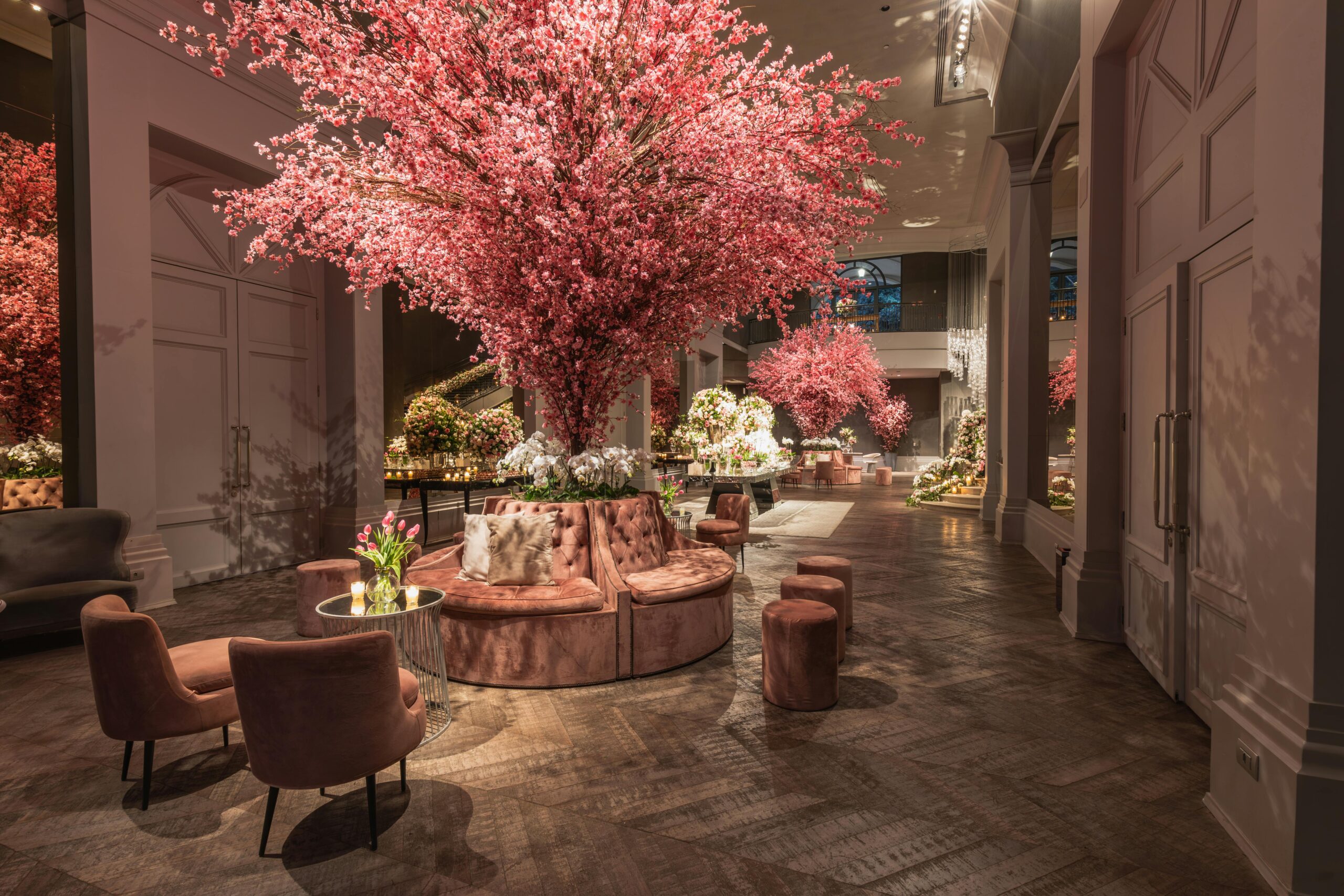 Elegant hotel lobby featuring cherry blossom arrangements and plush seating under warm lighting.