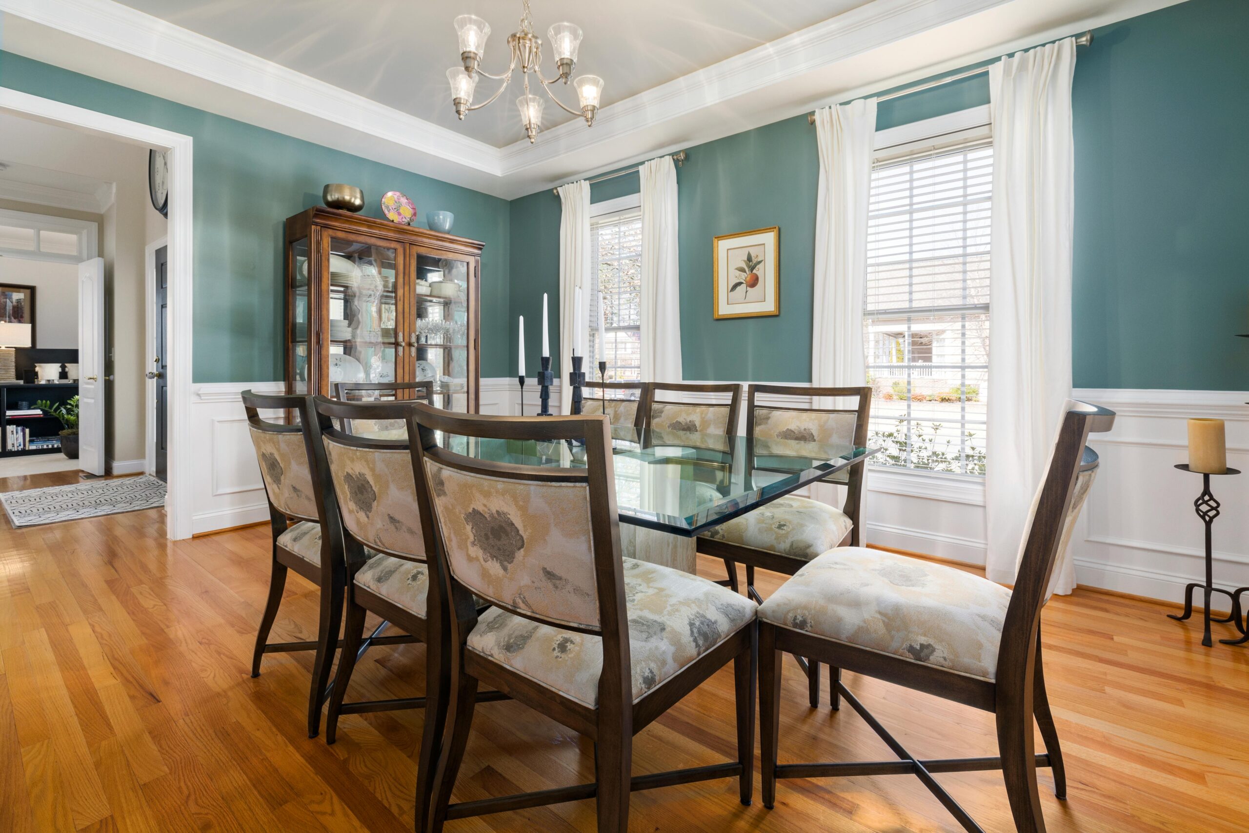 Spacious dining room featuring a glass table, wooden chairs, and a china cabinet, creating a cozy home interior ambiance.